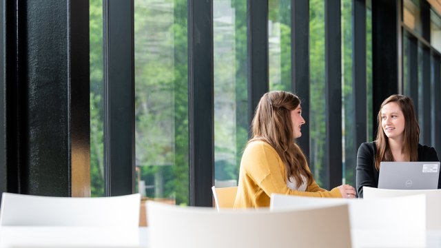 Zwei Frauen unterhalten sich an einem Tisch vor einem Fenster in der Great Lakes Cheese-Hauptverwaltung (Mittwoch, 26. Mai 2021, Hiram, Ohio, USA)
