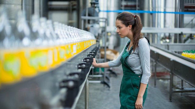 mujer monitorea la producción de botellas en la planta